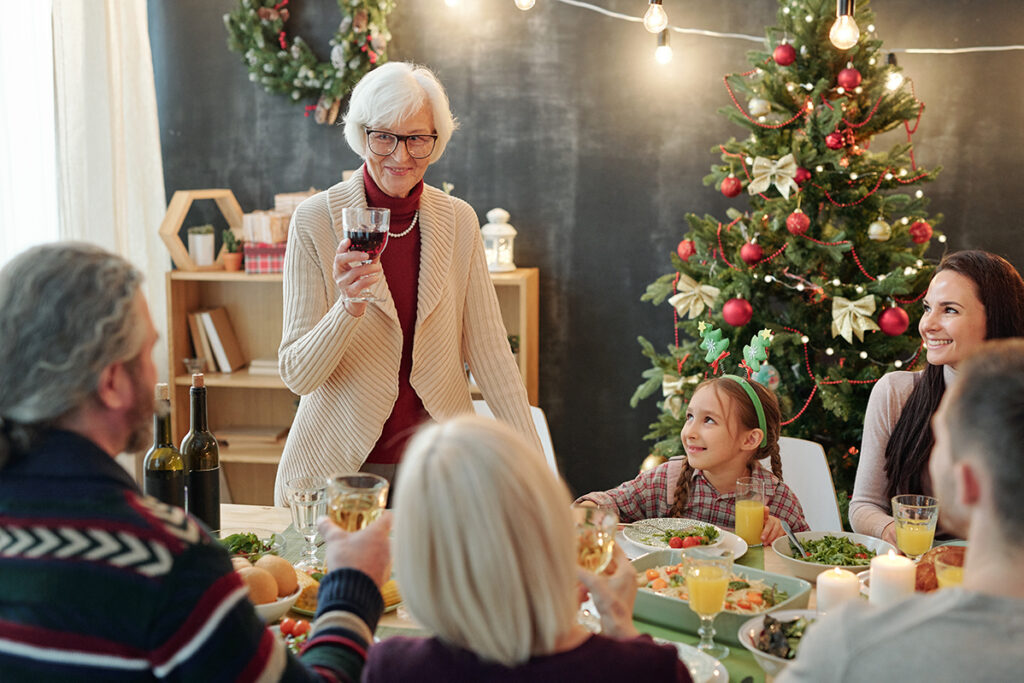 Legacy Ridge at Alpharetta | Happy senior woman with glass of wine making Christmas toast by family dinner