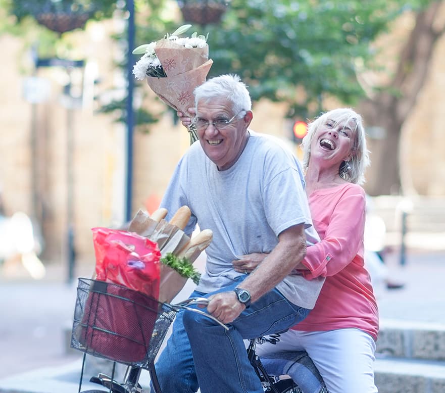 senior-man-and-woman-holding-up-bouquet-cycling