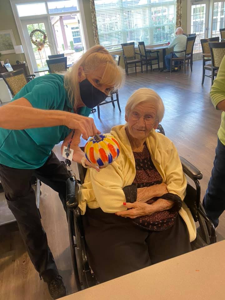 Atlas Senior Living | Resident and associate holding up a painted pumpkin