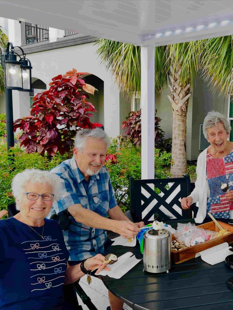 Three smiling residents enjoying an outdoor social activity at The Goldton at Venice, highlighting community connection, active senior living, and hurricane preparedness in senior living in Venice, FL