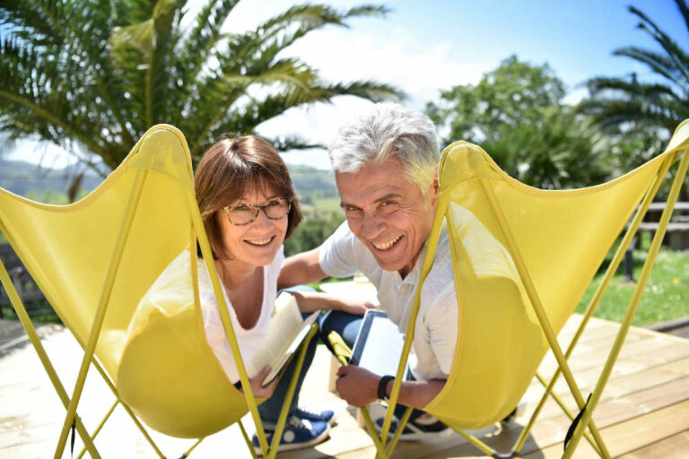 The Goldton at St. Petersburg | Senior couple lounging in lawn chairs surrounded by palm trees, outdoors
